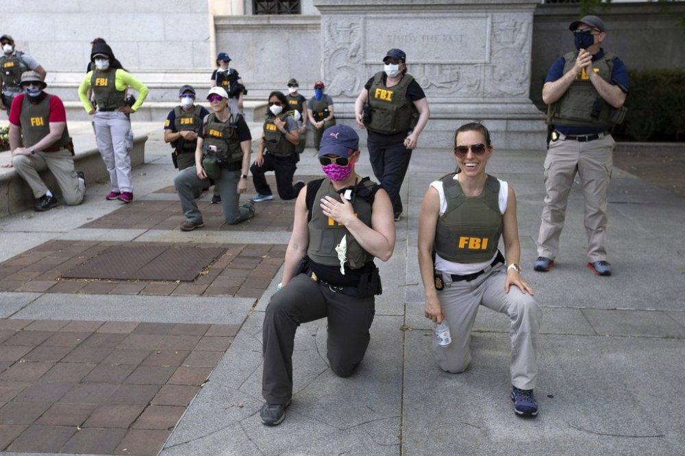 FILE - Federal Bureau of Investigation (FBI) officers take a knee with demonstrators, as they march on Pennsylvania Ave, June 4, 2020, in Washington, during a protest over the death of George Floyd, an unarmed black man, who died after a police officer kneeled on his neck for several minutes. (AP Photo/Jose Luis Magana, File)