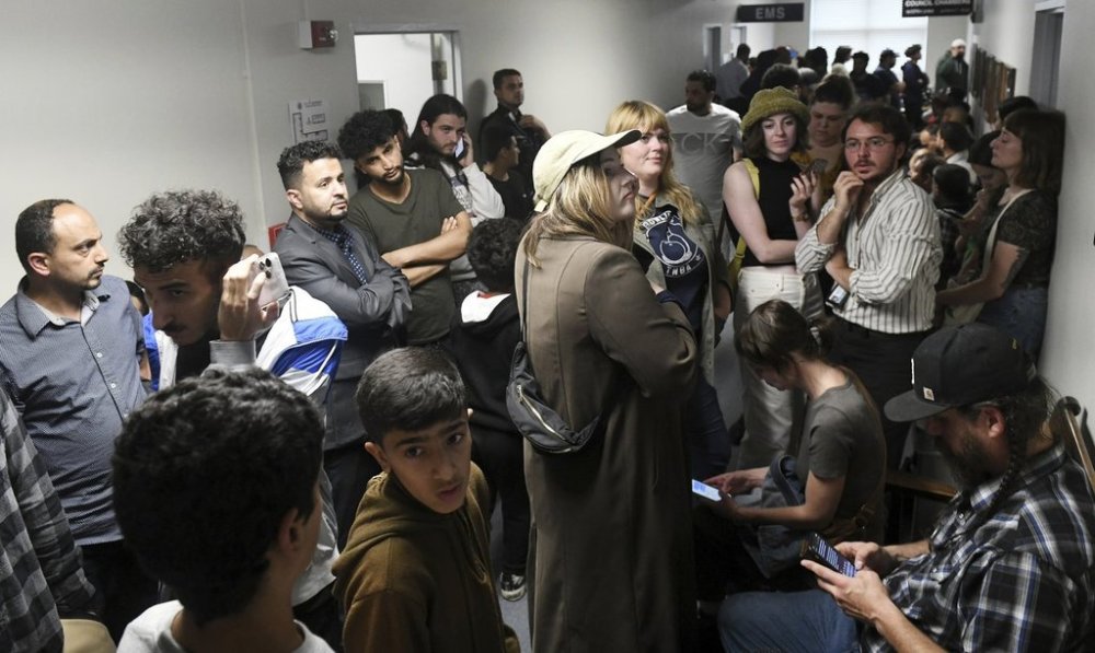 FILE - People who could not get into the Hamtramck city council chambers try to listen via YouTube or on the monitor in the hallway, during public comment on the flag neutrality law being considered by the city council in a meeting at City Hall in Hamtramck, Mich., June 13, 2023. (Robin Buckson/The Detroit News via AP, File)