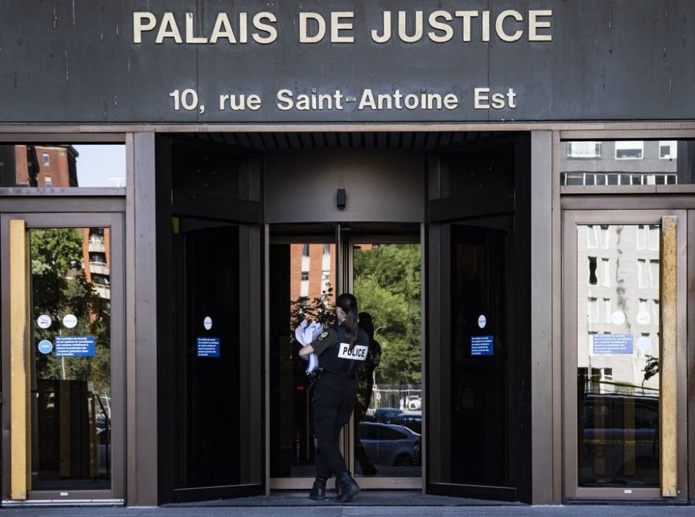 A police officer carries paperwork into the Palais de Justice, Quebec Superior Court, in Montreal on Monday, Aug. 18, 2025. THE CANADIAN PRESS/Christinne Muschi