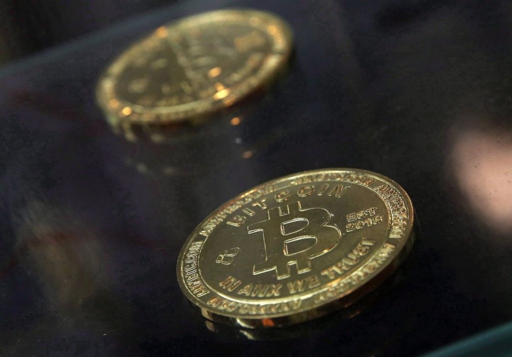 In this Friday, Dec. 8, 2017, photo, coins are displayed next to a Bitcoin ATM in Hong Kong. THE CANADIAN PRESS/AP /Kin Cheung