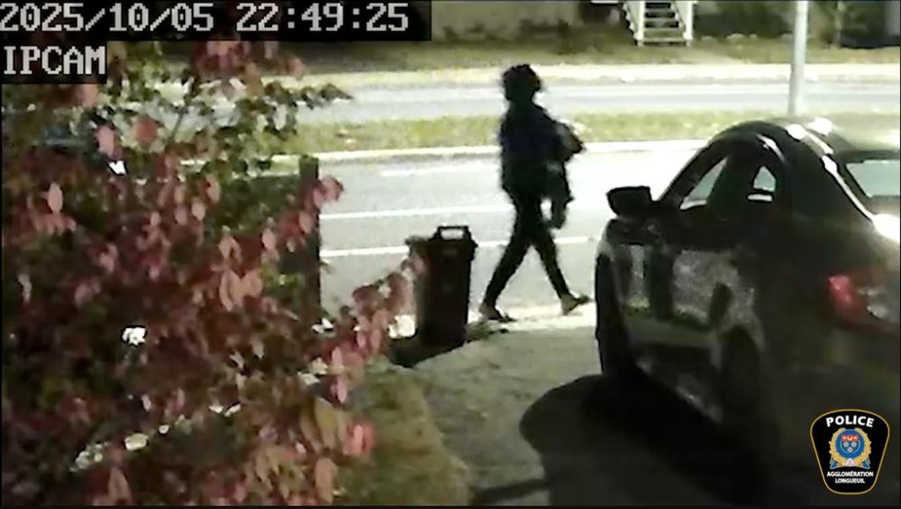 Longueuil police have released surveillance camera video in the hopes of tracking down the parents of a premature baby abandoned Sunday, Oct. 5, 2025, outside a home on Montreal's South Shore. This still image from the video shows a person walking down a dark sidewalk holding a cloth-wrapped bundle in their arms. THE CANADIAN PRESS/Handout - SPAL (Mandatory Credit)