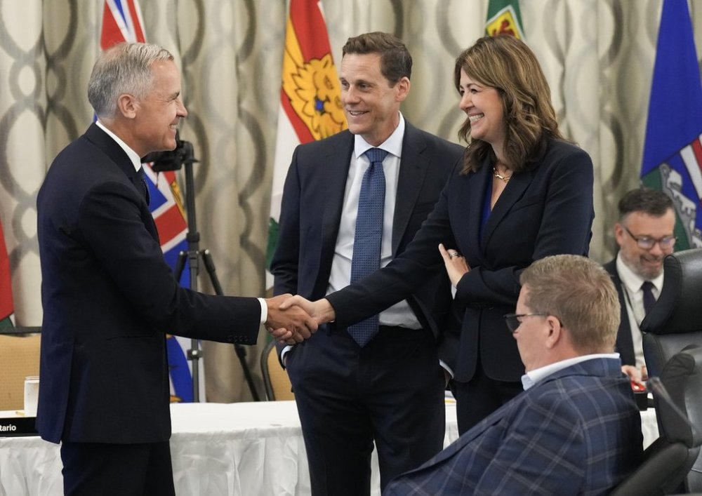 Canadian Prime Minister Mark Carney, left, greets Alberta Premier Danielle Smith, right, during the 2025 summer meetings of Canada's Premiers at Deerhurst Resort in Huntsville, Ont., on Tuesday, July 22, 2025. THE CANADIAN PRESS/Nathan Denette