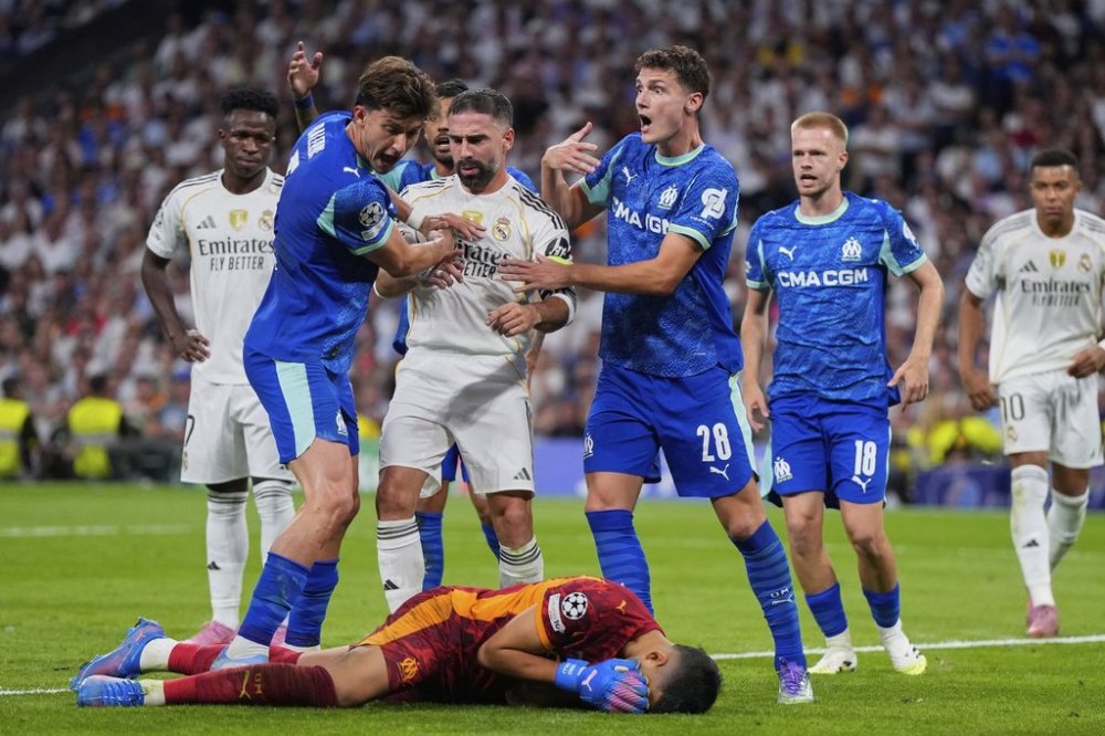 Marseille's goalkeeper Geronimo Rulli, bottom, gestures in pain after clashing with Real Madrid's Dani Carvajal, center, during a Champions League opening phase soccer match between Real Madrid and Marseille at Santiago Bernabeu stadium, in Madrid, Tuesday, Sept. 16, 2025. (AP Photo/Manu Fernandez)