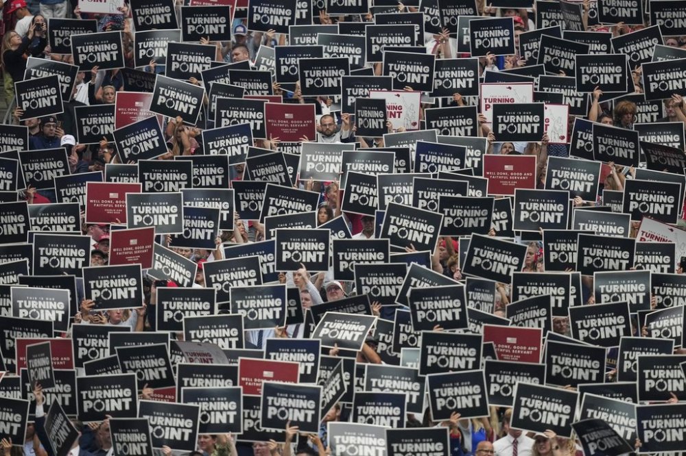 People hold up signs during a memorial for conservative activist Charlie Kirk, Sunday, Sept. 21, 2025, at State Farm Stadium in Glendale, Ariz. (AP Photo/John Locher)