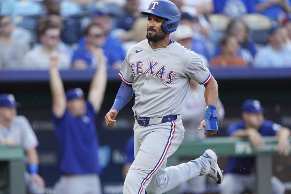 Texas Rangers' Marcus Semien runs home to score on an RBI single hit by Jonah Heim during the second inning of a baseball game against the Kansas City Royals, Monday, Aug. 18, 2025, in Kansas City, Mo. (AP Photo/Charlie Riedel)