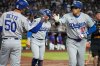 Los Angeles Dodgers' Shohei Ohtani, right, gets a high five from Mookie Betts, left, after hitting a home run against the Arizona Diamondbacks during the fourth inning of a baseball game Thursday, Sept. 25, 2025, in Phoenix. (AP Photo/Darryl Webb)