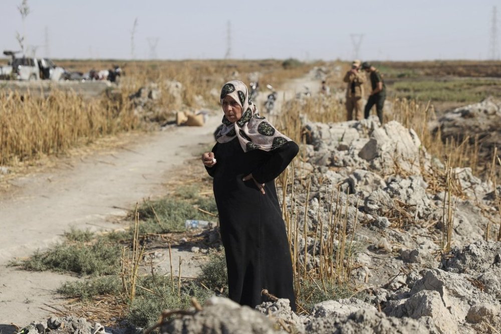 Samira Alloush, searching for her missing son, cries as she watches the Syrian Civil Defense workers inspect clothes found alongside human remains in Otaiba, on the outskirts of Damascus, Syria, Friday, Sept. 19, 2025. (AP Photo/Omar Albam)