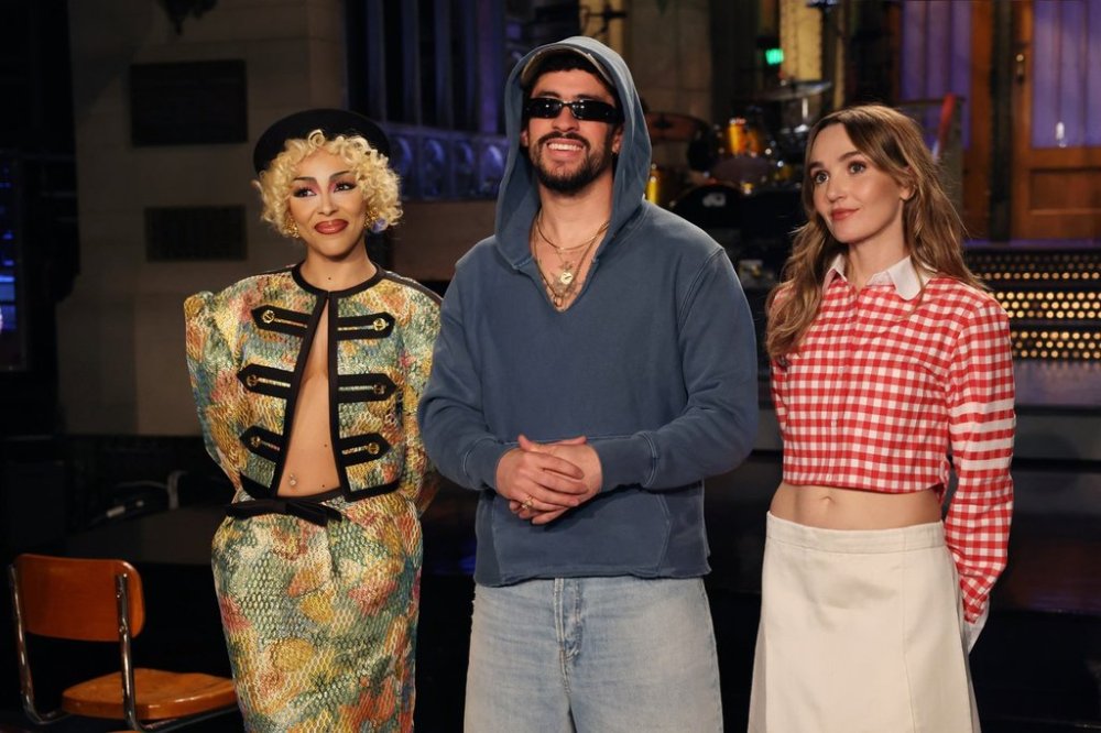 This image released by NBC shows host Bad Bunny, center, with musical guest Doja Cat, left, and cast member Chloe Fineman during the taping of promotional spots for the upcoming