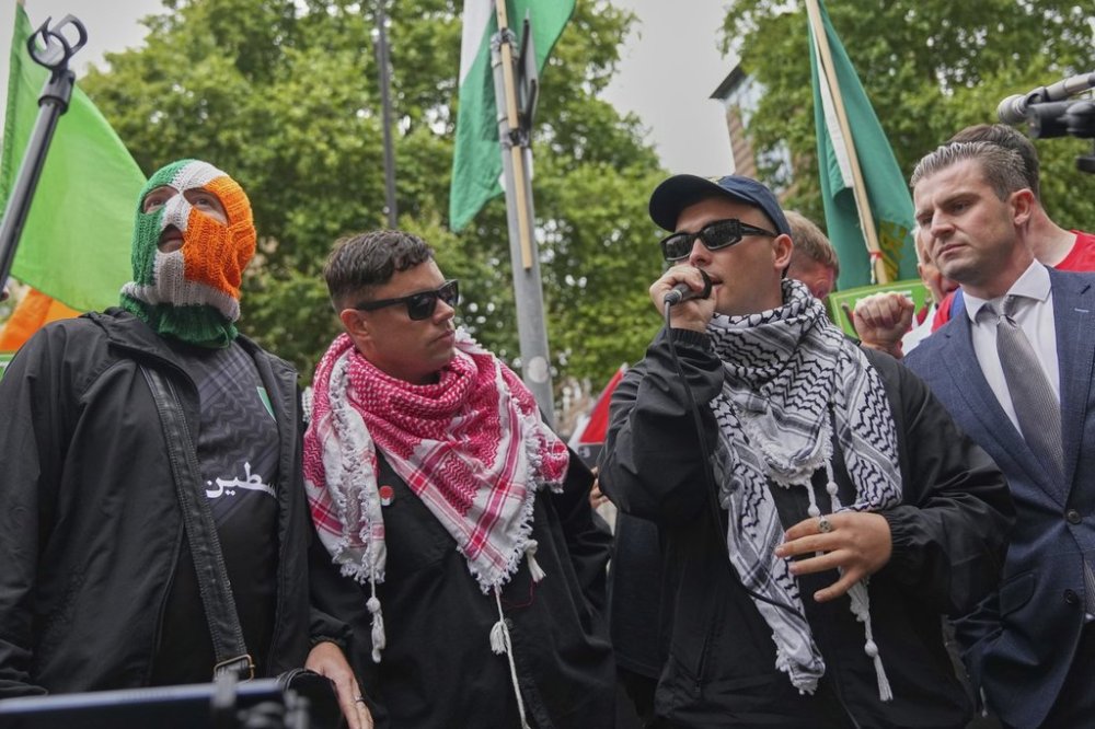 Liam Óg Ó hAnnaidh, a.k.a. Mo Chara, second right, a member of the Irish language band Kneecap, speaks to supporters as he departs Westminster Magistrates Court in London on Wednesday, Aug. 20, 2025. (AP Photo/Joanna Chan)