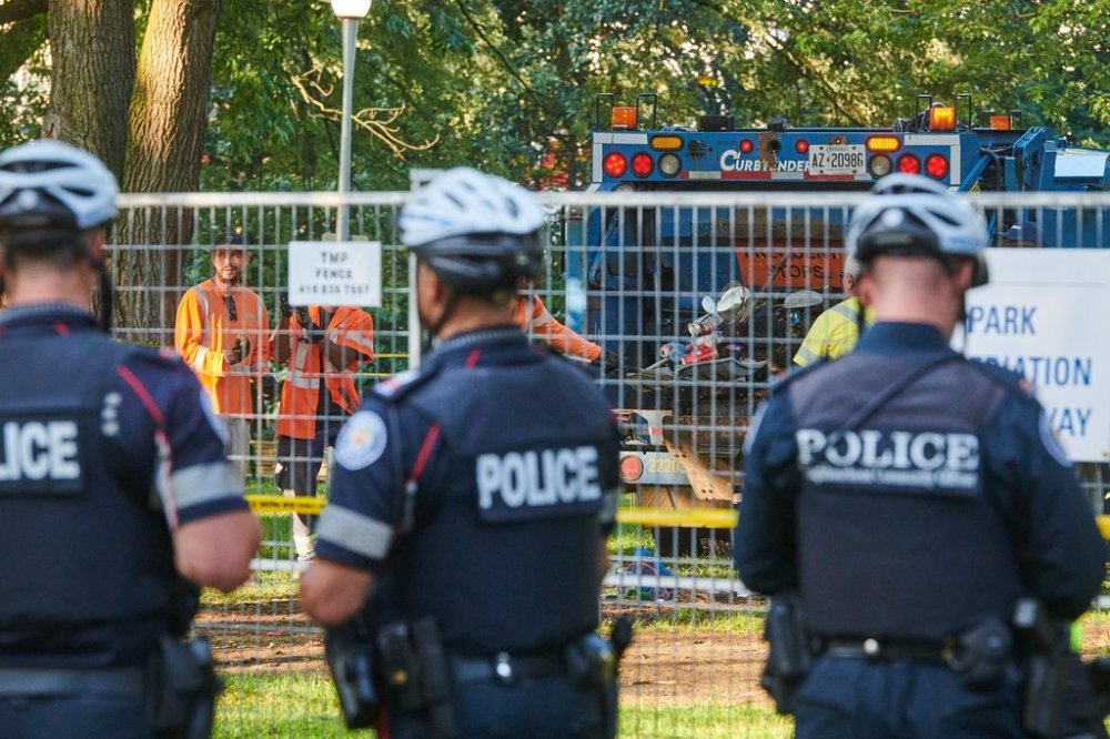 Security and police stand by as workers clear an encampment at Dufferin Grove Park in Toronto, on Friday, Sept. 26, 2025. THE CANADIAN PRESS/Sammy Kogan