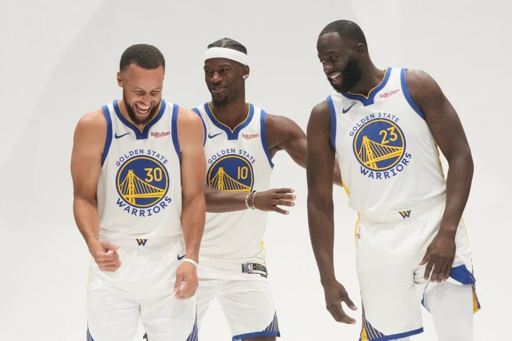 Golden State Warriors guard Stephen Curry, left, smiles while posing for photos with forward Jimmy Butler III, middle, and forward Draymond Green during the NBA basketball team's media day in San Francisco, Monday, Sept. 29, 2025. (AP Photo/Jeff Chiu)