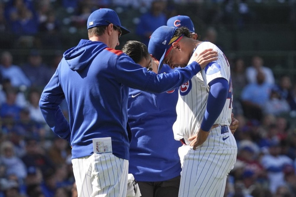 Chicago Cubs relief pitcher Daniel Palencia, right, is checked by a team trainer, center, and manager Craig Counsell, left, after an injury during the ninth inning of a baseball game against the Washington Nationals in Chicago, Sunday, Sept. 7, 2025. (AP Photo/Nam Y. Huh)