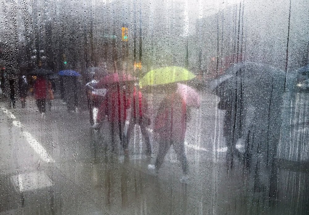 Pedestrians carrying umbrellas to shield themselves from the rain are seen through a cafe window covered with rain and steam in Vancouver, B.C., on Saturday March 11, 2017. THE CANADIAN PRESS/Darryl Dyck