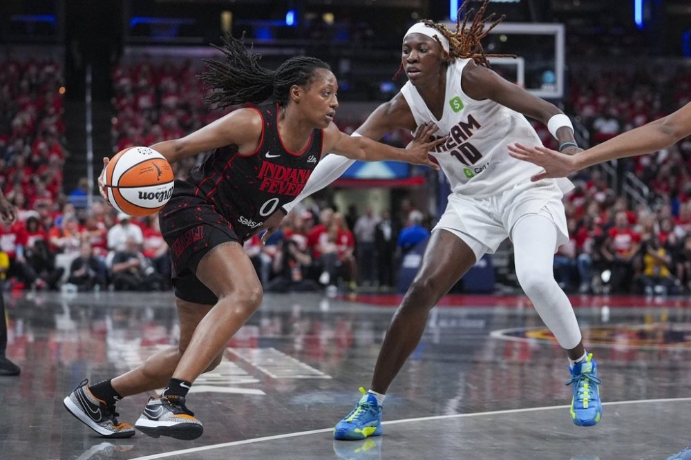 Indiana Fever guard Kelsey Mitchell (0) holds off Atlanta Dream guard Rhyne Howard (10) as she drives in the second half of a WNBA basketball playoff game in Indianapolis, Tuesday, Sept. 16, 2025. (AP Photo/Michael Conroy)