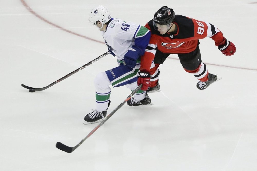 Vancouver Canucks defenceman Quinn Hughes (43) fights for control of the puck with New Jersey Devils centre Jack Hughes (86) during the third period of an NHL hockey game Saturday, Oct. 19, 2019, in Newark, N.J. (AP Photo/Frank Franklin II)