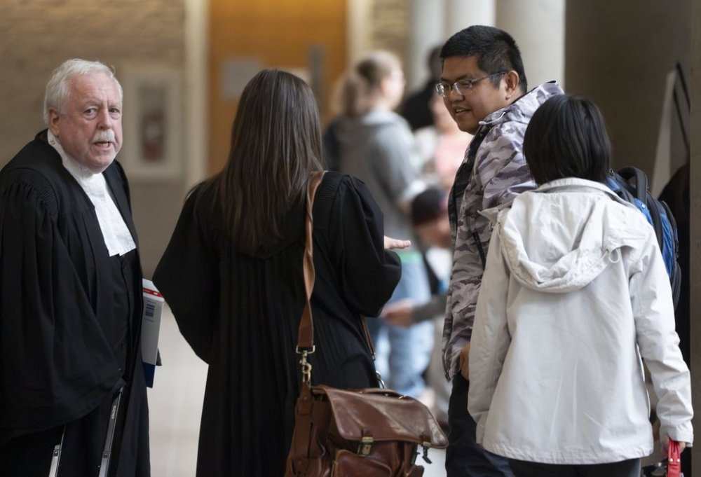 Defence lawyer Gary Martin, left, meets his client Yuesheng Wang and his partner as they arrive for his espionage trial at the Longueuil courthouse in Longueuil, Que., on Monday, Oct. 6, 2025. THE CANADIAN PRESS/Christinne Muschi