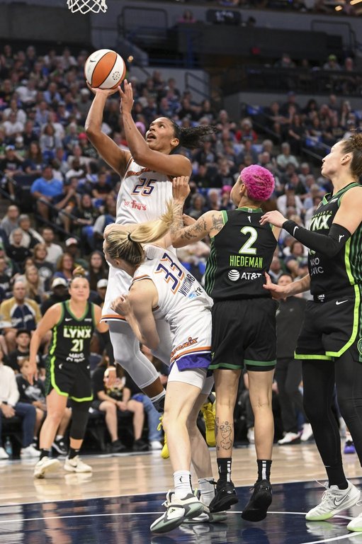 Phoenix Mercury forward Alyssa Thomas (25) goes up for a shot over guard Sami Whitcomb (33) and Minnesota Lynx guard Natisha Hiedeman (2) during the first half of Game 1 of a WNBA basketball playoff semifinals series Sunday, Sept. 21, 2025, in Minneapolis. (AP Photo/Craig Lassig)