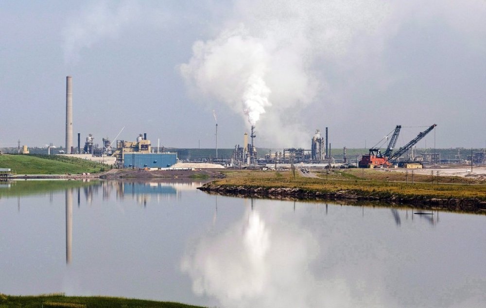 An oilsands facility is reflected in a tailings pond near Fort McMurray, Alta., on July 10, 2012. THE CANADIAN PRESS/Jeff McIntosh