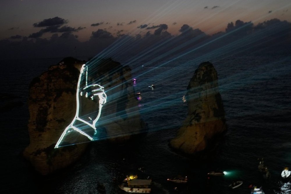 The landmark Raouche sea rock is illuminated by the hand of the late Hezbollah leader Sayyed Hassan Nasrallah during an event commemorating his death in Israeli airstrikes nearly a year ago, in Beirut, Lebanon, Thursday, Sept. 25, 2025. (AP Photo/Hussein Malla)