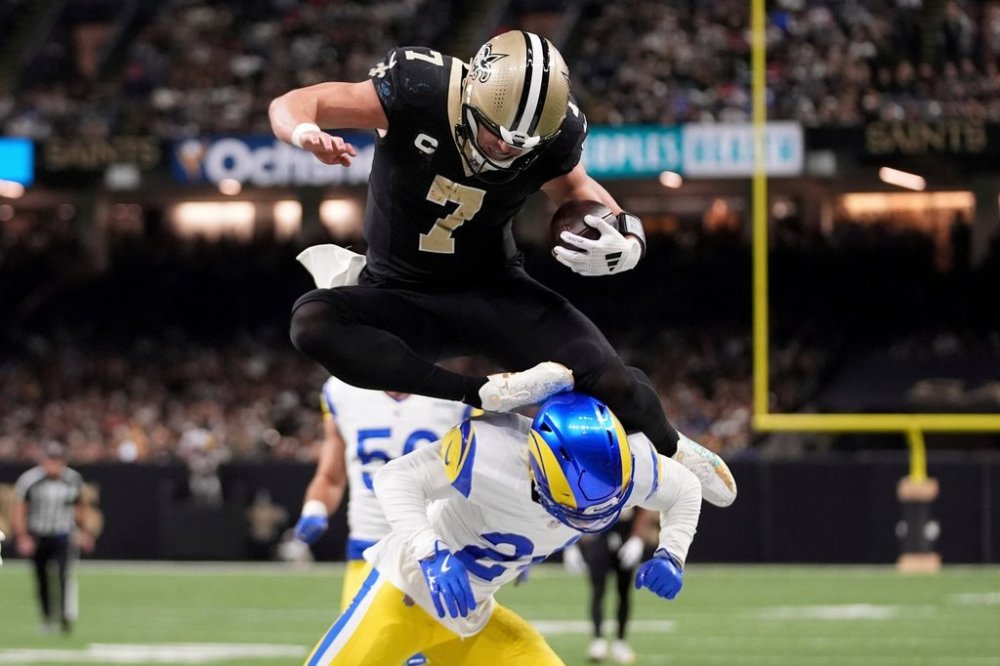 FILE - New Orleans Saints tight end Taysom Hill (7) leaps over Los Angeles Rams cornerback Darious Williams, bottom, during the first half of an NFL football game Dec. 1, 2024, in New Orleans. (AP Photo/Gerald Herbert, File)
