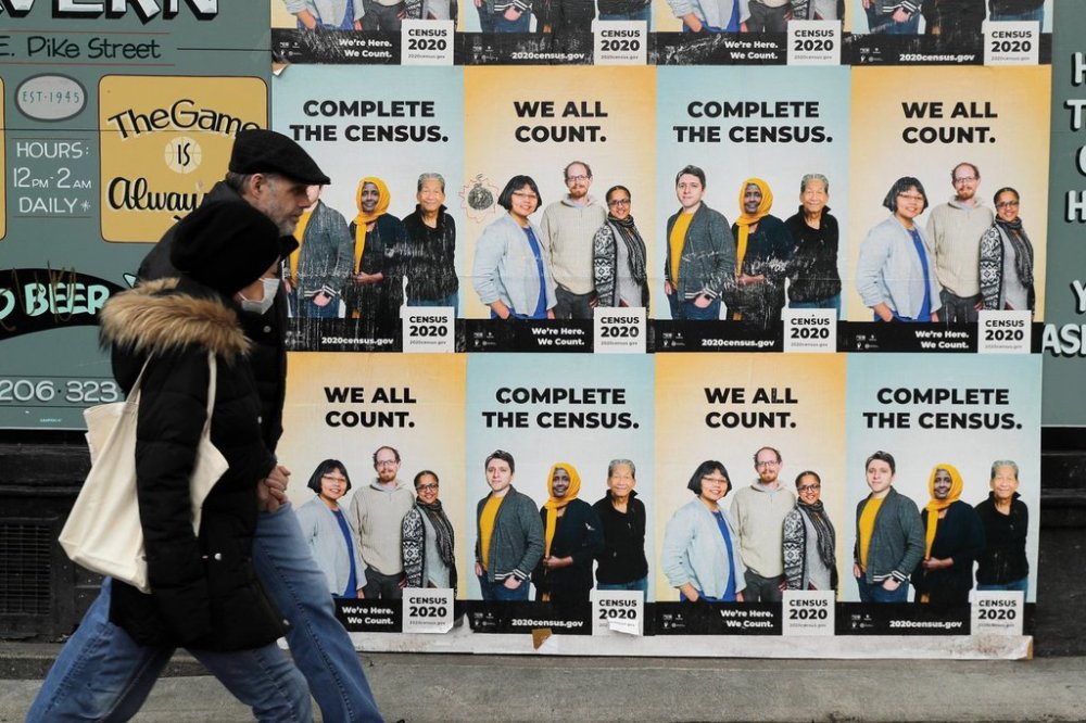 FILE - In this Wednesday, April 1, 2020 file photo,People walk past posters encouraging participation in the 2020 Census in Seattle's Capitol Hill neighborhood. (AP Photo/Ted S. Warren, File)
