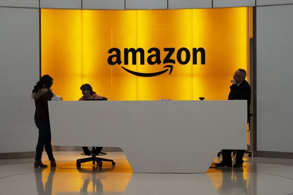 FILE - People stand in the lobby for Amazon offices in New York, Feb. 14, 2019. (AP Photo/Mark Lennihan, File)