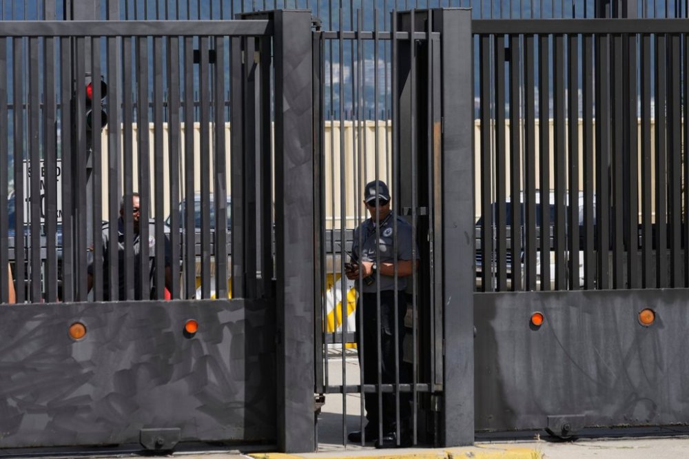 Security officers stand behind the main gate of the United States embassy in Caracas, Venezuela, Monday, Oct. 27, 2025. (AP Photo/Ariana Cubillos)