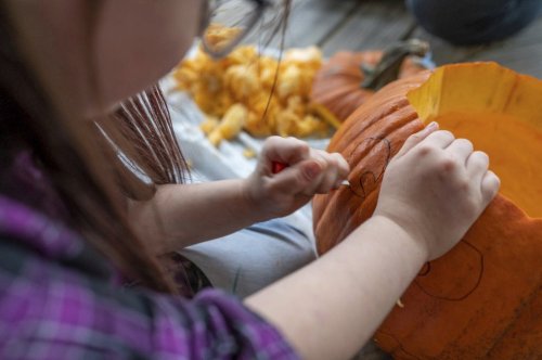 FILE - A kid carves a pumpkin on the front porch of her home Oct 20, 2023, in Auburn, Maine. (Andree Kehn/Sun Journal via AP, File)