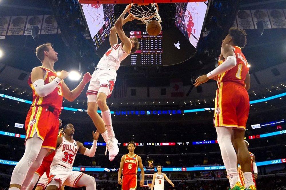 Chicago Bulls forward Matas Buzelis, center, dunks the ball on Atlanta Hawks guard Luke Kennard, left, and forward Jalen Johnson during the second half of an NBA basketball game Monday, Oct. 27, 2025, in Chicago. (AP Photo/David Banks)