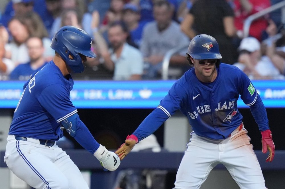 Toronto Blue Jays' Andrés Giménez, left, and teammate Ernie Clement celebrate at home plate after Clements scored on a sacrifice fly from Giménez against the Tampa Bay Rays during fourth inning MLB baseball action in Toronto on Sunday Sept. 28, 2025. THE CANADIAN PRESS/Chris Young