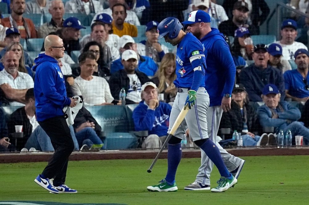 Toronto Blue Jays' George Springer leaves the game with an injury with manager John Schneider, right, during the seventh inning in Game 3 of baseball's World Series against the Los Angeles Dodgers, Monday, Oct. 27, 2025, in Los Angeles. (AP Photo/David J. Phillip)