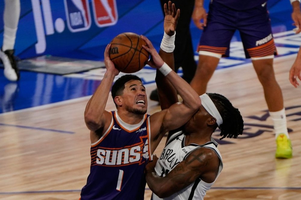 Brooklyn Nets guard/forward Terance Mann (14) guards Phoenix Suns guard Devin Booker (1) during a preseason NBA basketball game between Phoenix Suns and Brooklyn Nets in Macao, Friday, Oct. 10, 2025. (AP Photo/Vernon Yuen)