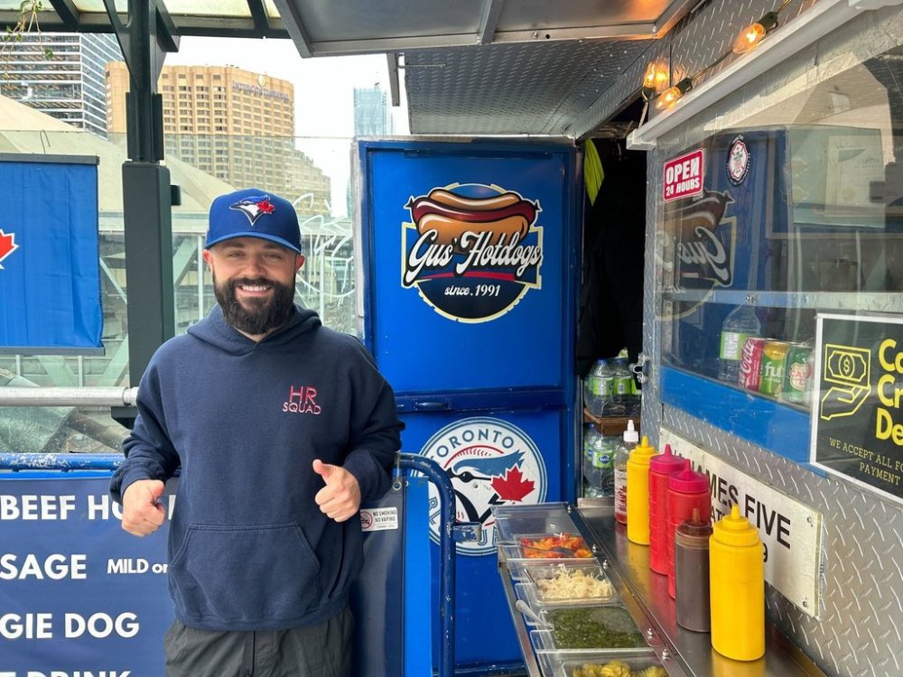 Johnny Prokos poses at his dad’s hot dog stand on the east side of Rogers Centre in Toronto, on Monday, Oct. 20, 2025. He describes the stadium as a second home to him and his dad and has been to over 500 games. THE CANADIAN PRESS/Cassidy McMackon