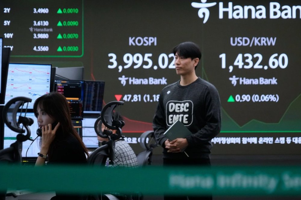A currency trader talks on the phone near a screen showing the Korea Composite Stock Price Index (KOSPI) and the foreign exchange rate between U.S. dollar and South Korean won, right, at the foreign exchange dealing room of the Hana Bank headquarters in Seoul, South Korea, Tuesday, Oct. 28, 2025. (AP Photo/Ahn Young-joon)