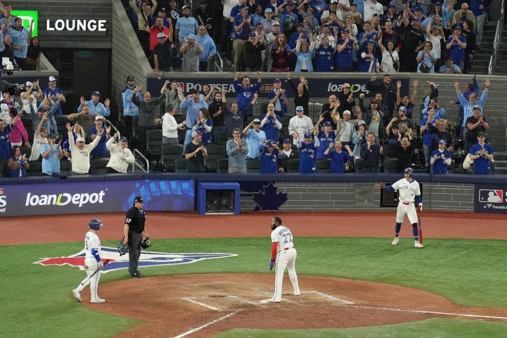 Blue Jays first baseman Vladimir Guerrero Jr. (27) reacts after scoring on a wild throw by Seattle Mariners catcher Cal Raleigh (29) during the seventh inning of Game 6 of baseball's American League Championship Series in Toronto on Oct. 19, 2025. THE CANADIAN PRESS/Chris Young