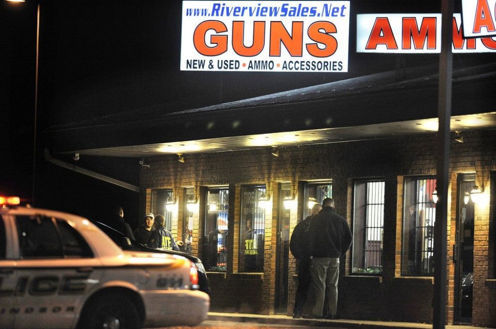 FILE - In this Dec. 20, 2012 file photo, law enforcement officials stand outside Riverview Gun Sales, as authorities raid the store in East Windsor, Conn. (AP Photo/Jessica Hill, File)