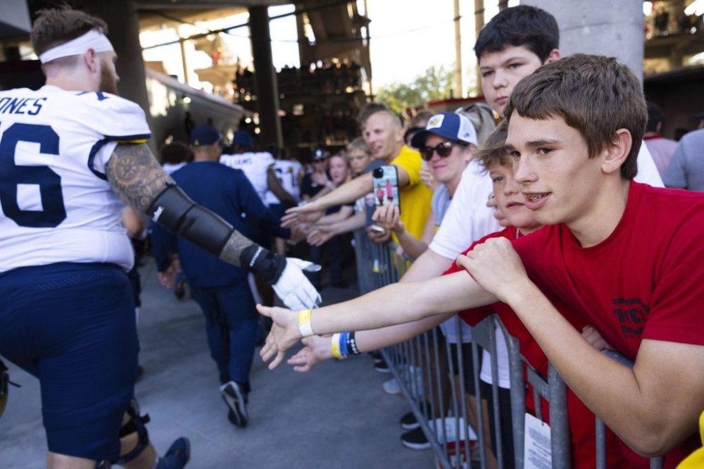 Nebraska fan Kellen Otto, 15, right, of Firth, Neb., high fives Michigan players as they exit the field following Michigan's 30-27 win over Nebraska in an NCAA college football game, Saturday, Sept. 20, 2025, in Lincoln, Neb. (AP Photo/Rebecca S. Gratz)