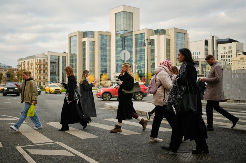 People cross a street, with Russian oil company Lukoil's headquarters seen in the background, in Moscow, Russia, Thursday, Oct. 23, 2025. (AP Photo/Pavel Bednyakov)