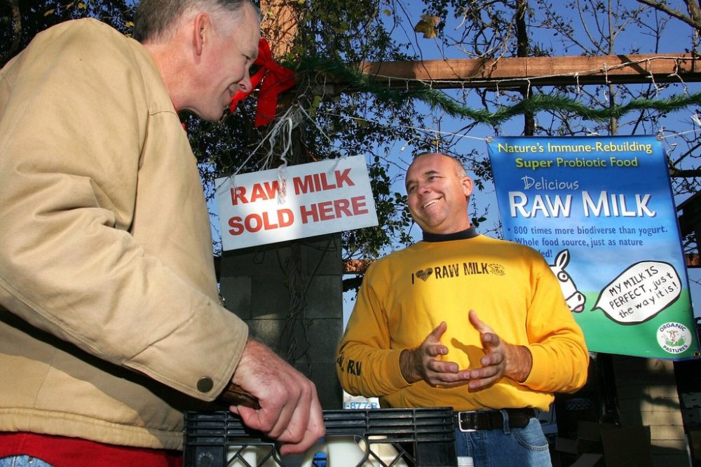 FILE - Veterinarian Patrick Smith, left, discusses raw milk with dairyman and producer Mark McAfee at the Farmer's Market in Fresno, Calif., on Saturday, Dec. 22, 2007. (AP Photo/Gary Kazanjian, File)