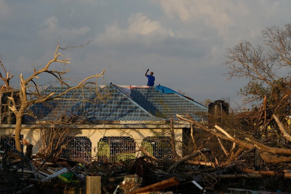 A man searches for cell signal from the roof of his house flooded and damaged by Hurricane Melissa in Black River, Jamaica, Thursday, Oct. 30, 2025. (AP Photo/Matias Delacroix)