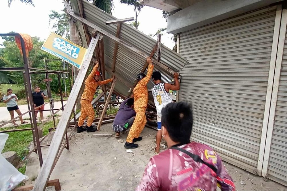 In this photo provided by the Bureau of Fire Protection, firefighters and residents hold on a toppled structure following a strong earthquake in Davao Oriental province, southern Philippines on Friday Oct. 10, 2025. (Bureau of Fire Protection via AP)