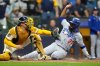 Los Angeles Dodgers' Teoscar Hernández is forced out at home by Milwaukee Brewers catcher William Contreras during the fourth inning in Game 1 of baseball's National League Championship Series, Monday, Oct. 13, 2025, in Milwaukee. (AP Photo/Brynn Anderson)