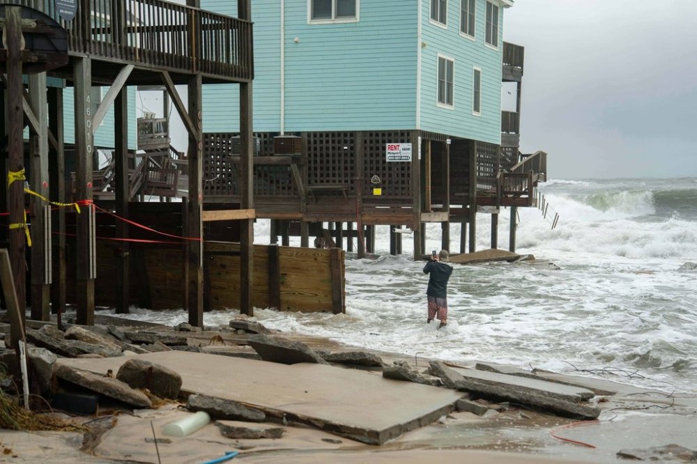 A homeowner takes a photo after a storm, Monday, Oct. 13, 2025, in Buxton, N.C. (AP Photo/Allison Joyce)