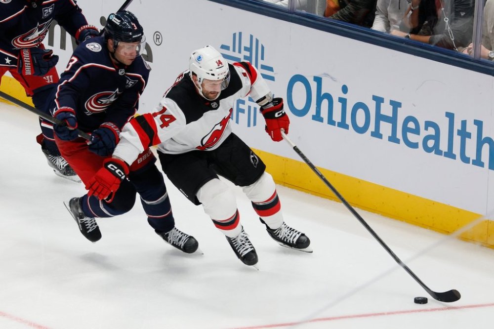 New Jersey Devils' Luke Glendening, right, keeps the puck away from Columbus Blue Jackets' Charlie Coyle, left, during the third period of an NHL hockey game, Monday, Oct. 13, 2025, in Columbus, Ohio. (AP Photo/Jay LaPrete)
