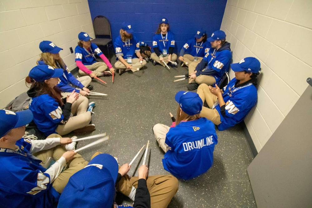 Members warm up by playing their drum sticks on the floor. (Brook Jones / Free Press)