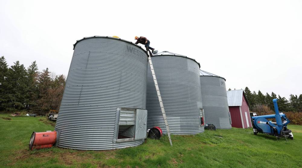 Colin Penner closes one of the hatch doors to a granary on his farm. (Ruth Bonneville / Free Press)