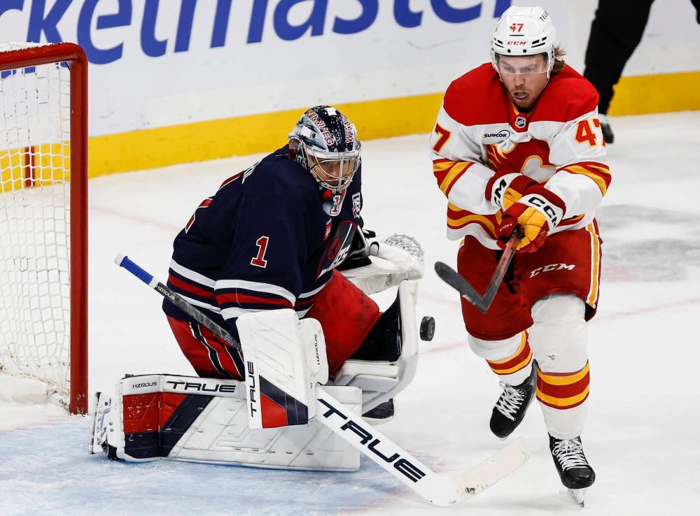 JOHN WOODS / THE CANADIAN PRESS
Calgary Flames' Connor Zary knocks down his own rebound off Winnipeg Jets goaltender Eric Comrie during the second perio in Winnipeg on Friday.