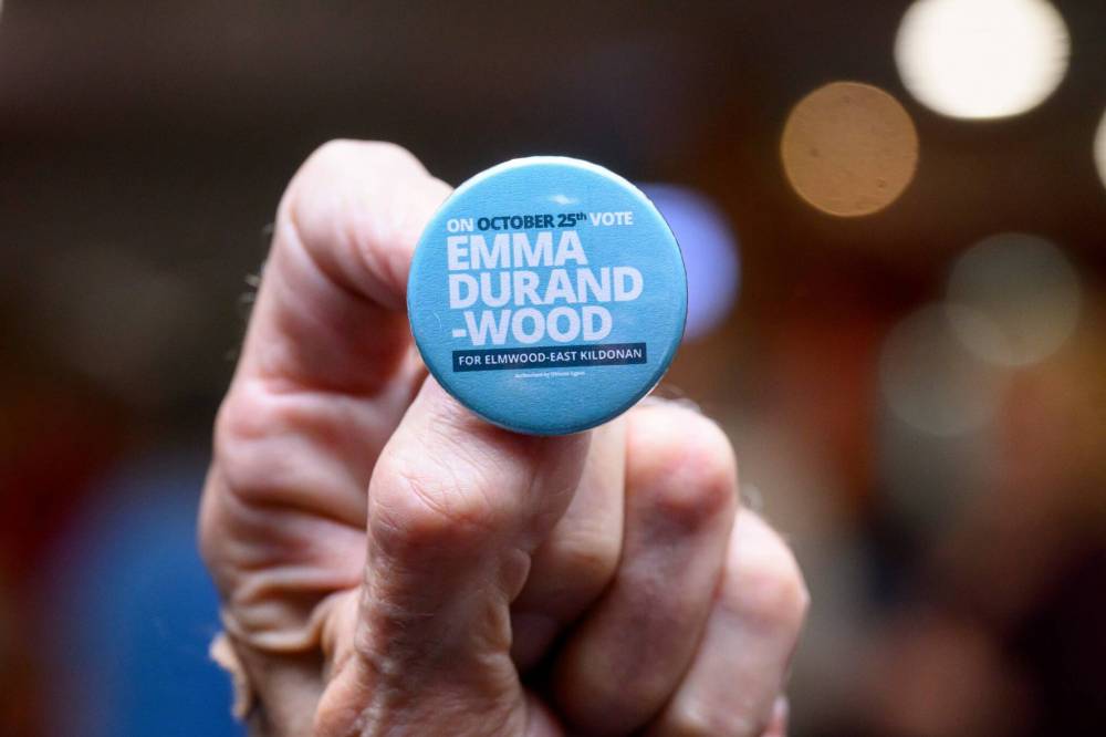 MIKE SUDOMA/WINNIPEG FREE PRESS A supporter of candidate Emma Durand-Wood holds a campaign pin Saturday night at the Elmwood Curling Club.