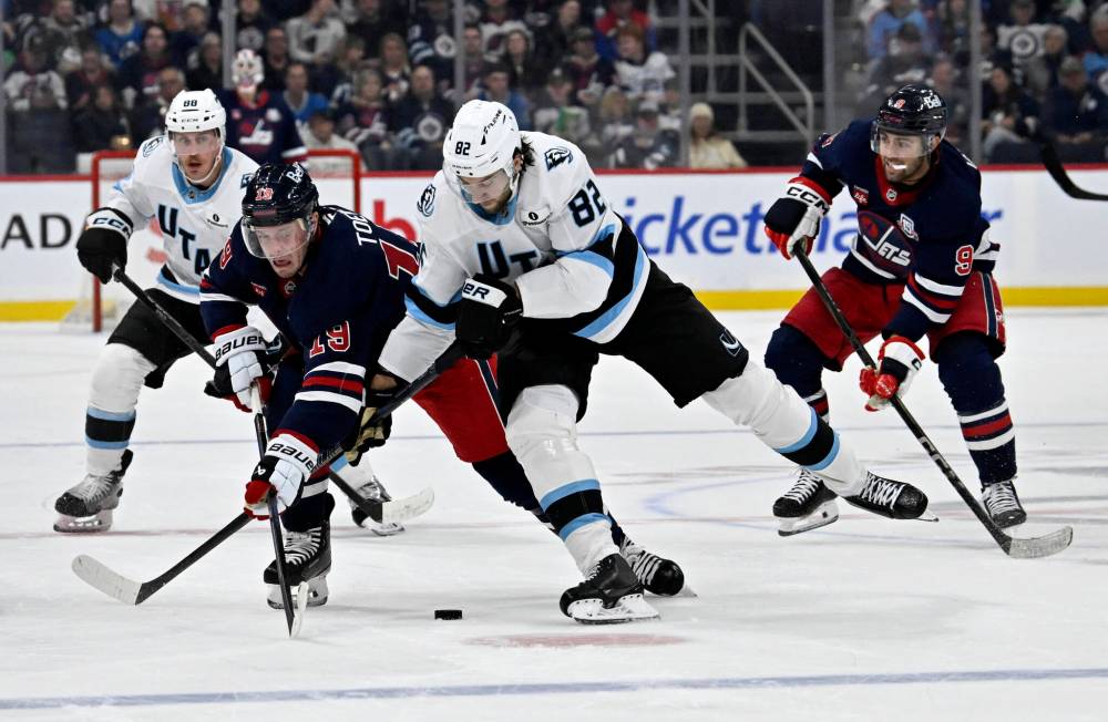 Winnipeg Jets’ Jonathan Toews (19) and Utah Mammoth Kevin Stenlund (82) battle for the puck during the second period of their NHL hockey game in Winnipeg, Sunday, Oct. 26, 2025. (Fred Greenslade / The Canadian Press)