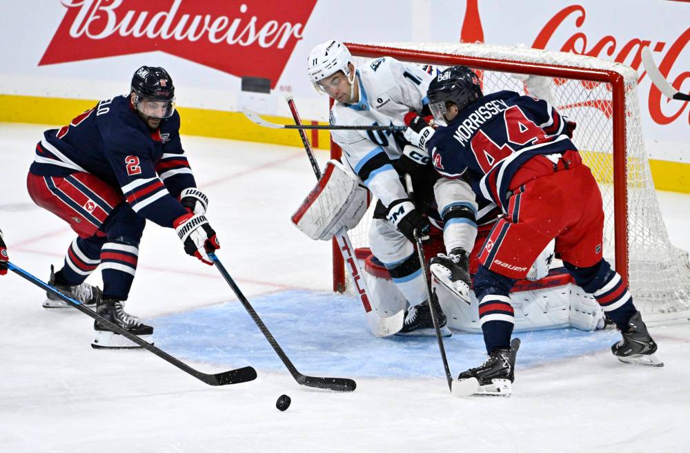 Winnipeg Jets’ Dylan DeMelo (2) and Josh Morrissey (44) defend against Utah Mammoth Dylan Guenther (11) during the third period. (Fred Greenslade / The Canadian Press)